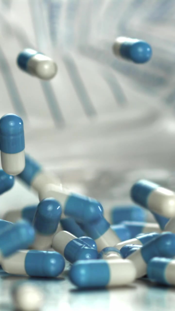 Capsule di medicinale blu e bianche che cadono al rallentatore