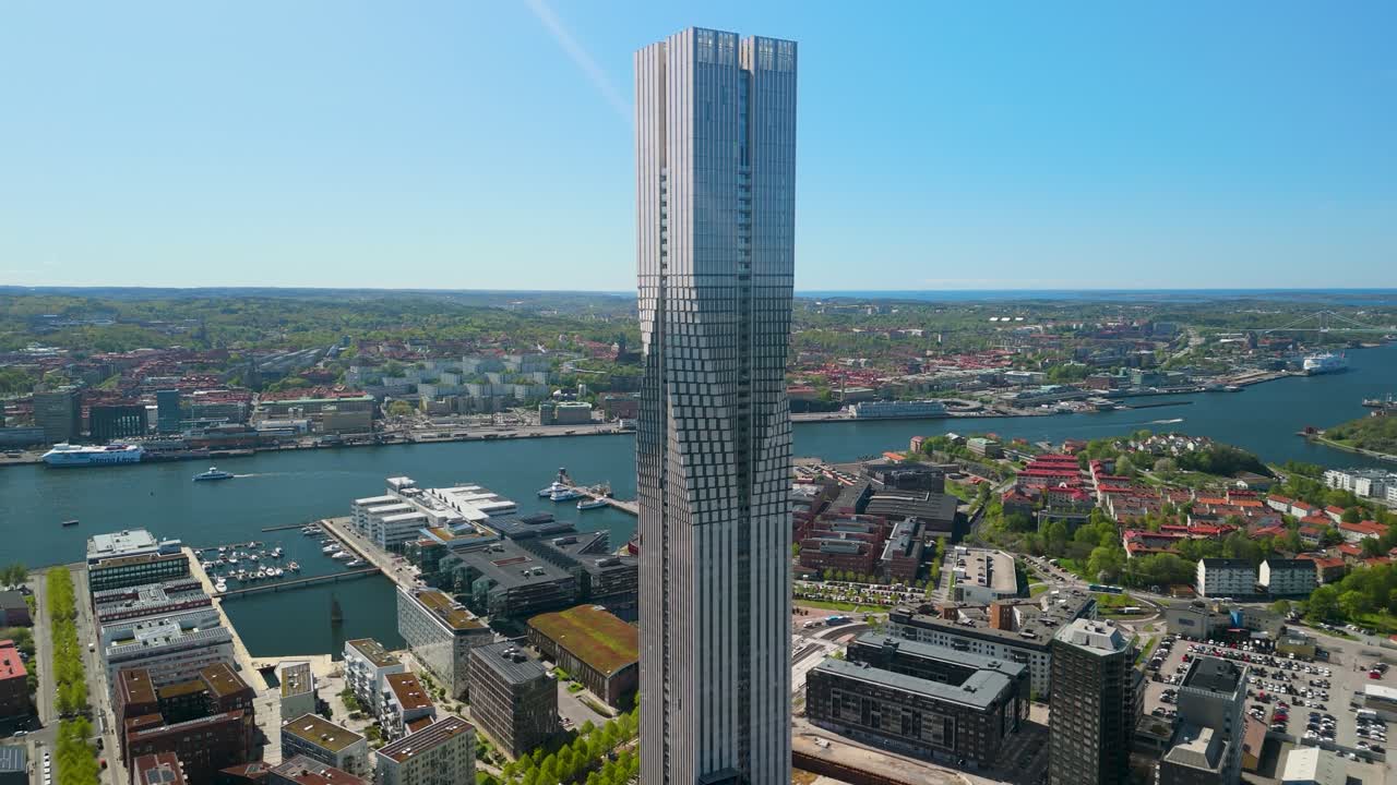 Un drone che si allontana salendo rivela il grattacielo Karlatornet che domina il lungofiume del Göta, con l'espansione urbana di Göteborg, il porto turistico e l'isola di Hisingen in estate