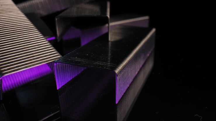 Extreme close up panning a pile of staples with a dark background accented by a reflecting purple light