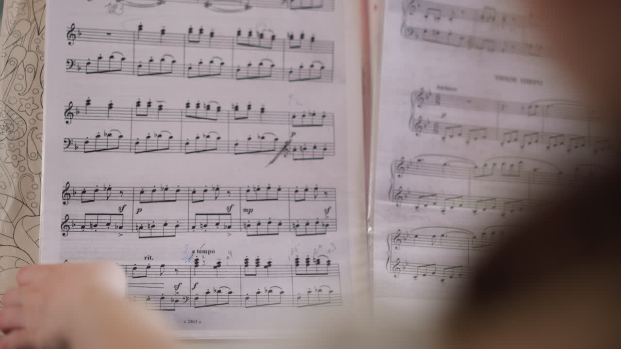 молодой музыкант просматривает ноты, играя на фортепиано