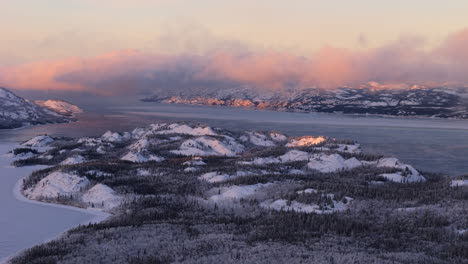 snowy mountain range around the lake laberge during winter in yukon, canada. - aerial shot