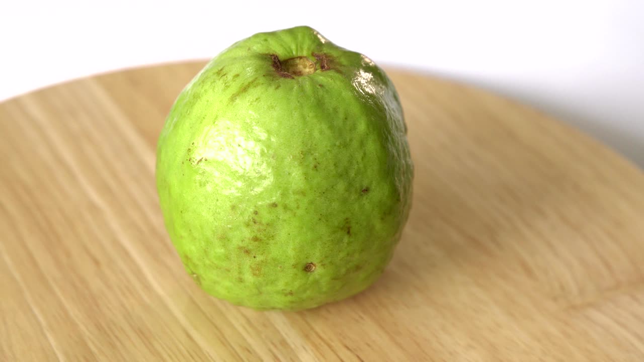 la guayaba gira sobre una mesa de madera y un fondo blanco