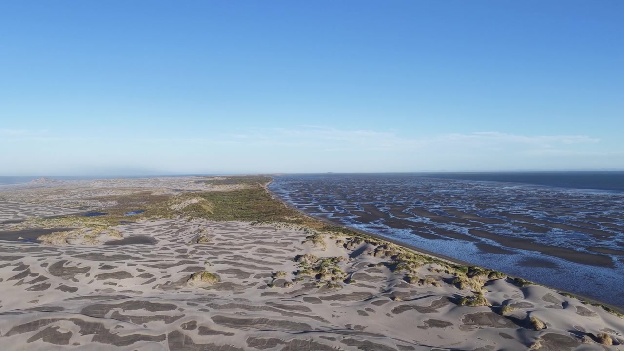 Bugtende tidevandskanaler skærer sig igennem store sandflader og klitter langs kysten, Sydøen, New Zealand.