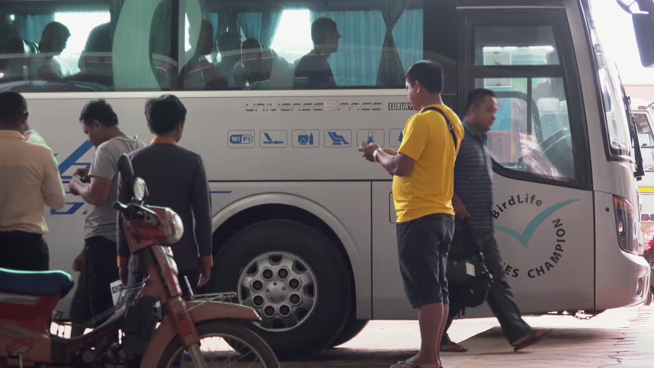 Passengers and a scooter at a bus stop with a white luxury bus