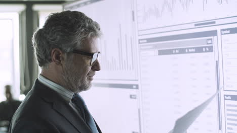 professional senior businessman standing in front of big screen with important documents