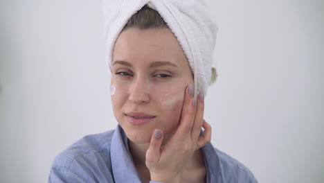 portrait of young woman applying moisturizer