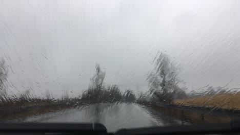 interior view from a car driving on a right side of the road in heavy rain