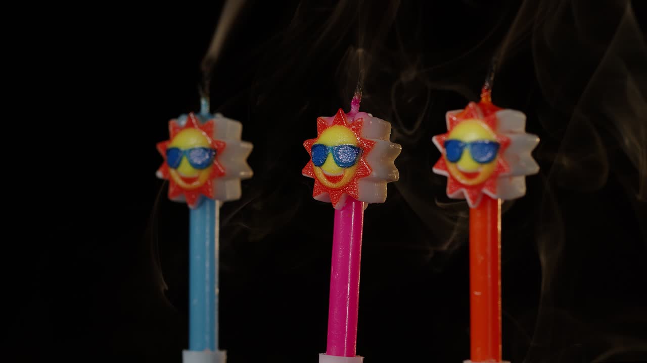 Candele festive di compleanno a forma di sole con occhiali da sole che girano, ruotano, isolate su sfondo nero