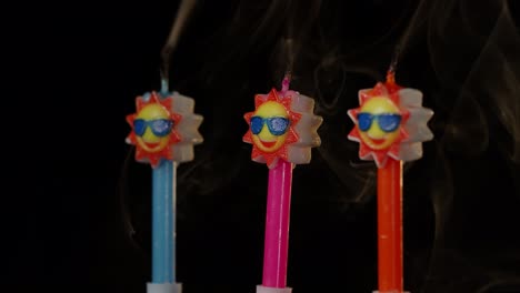 Birthday-festive-candles-in-form-of-sun-in-sunglasses-turning,-spinning-isolated-on-black-background