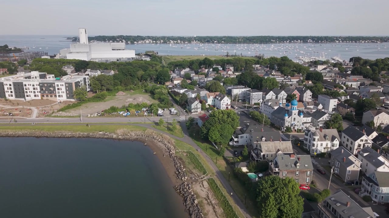 Salem, Massachusetts, porto costiero, acqua calma, costa con molo in pietra, case sul lungomare, quartiere residenziale, ciminiera di una centrale elettrica, paesaggio costiero del New England. Ripresa aerea con drone