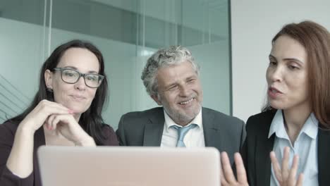 empresarios sonrientes hablando en video con sus socios a través de una computadora portátil