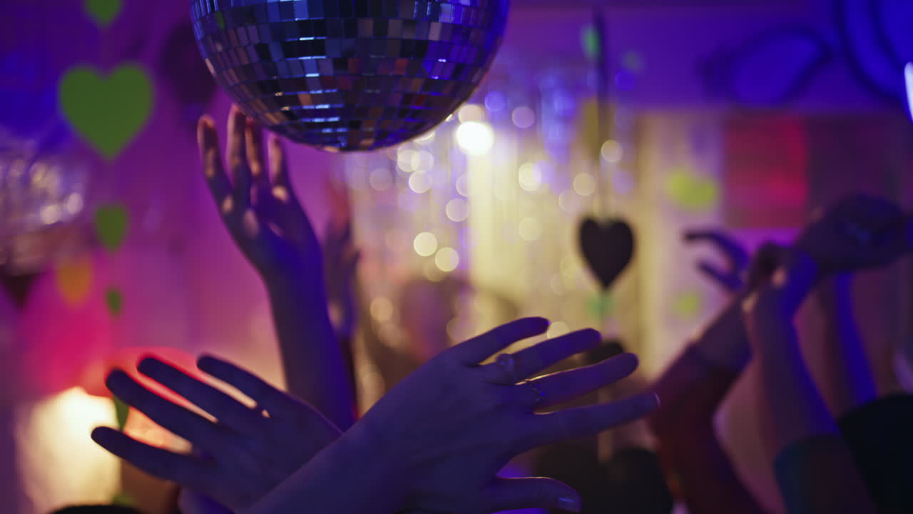 Clubbing people hands dancing in neon light nightclub closeup. Energetic arms
