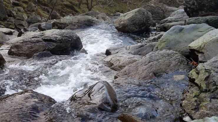 Mevsimlik sonbahar ormanında kayalar üzerinden akan kayalık şelale deresi, sağa kaydırma.