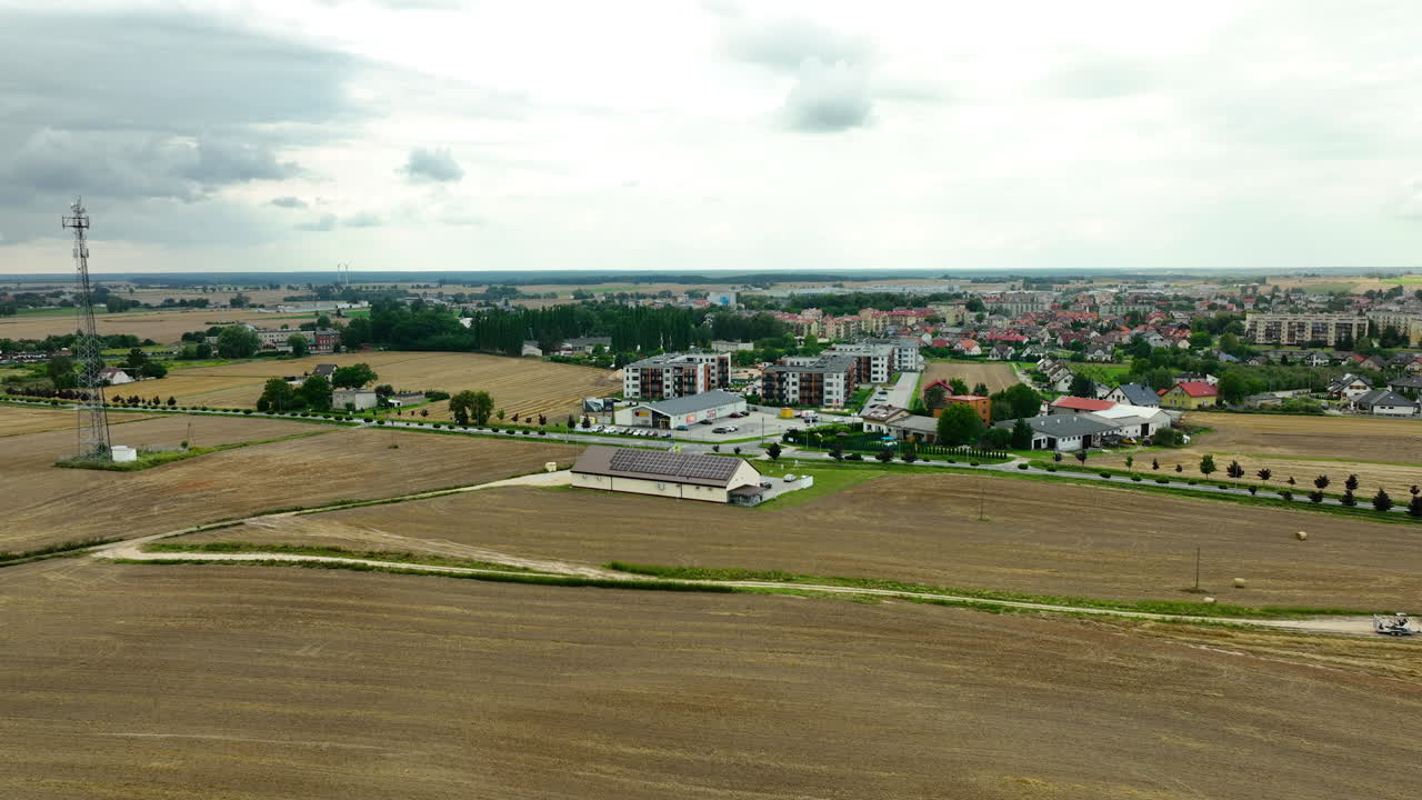 fotografía aérea de gran ángulo de una pequeña ciudad rodeada de campos agrícolas, con un nuevo complejo residencial visible en el centro