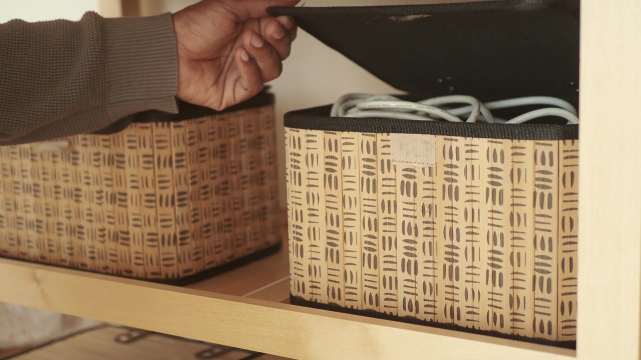 Person Removing a Woven Storage Box from a Wooden Shelf