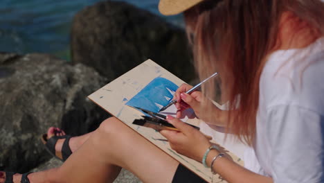 woman painting seascape on the beach