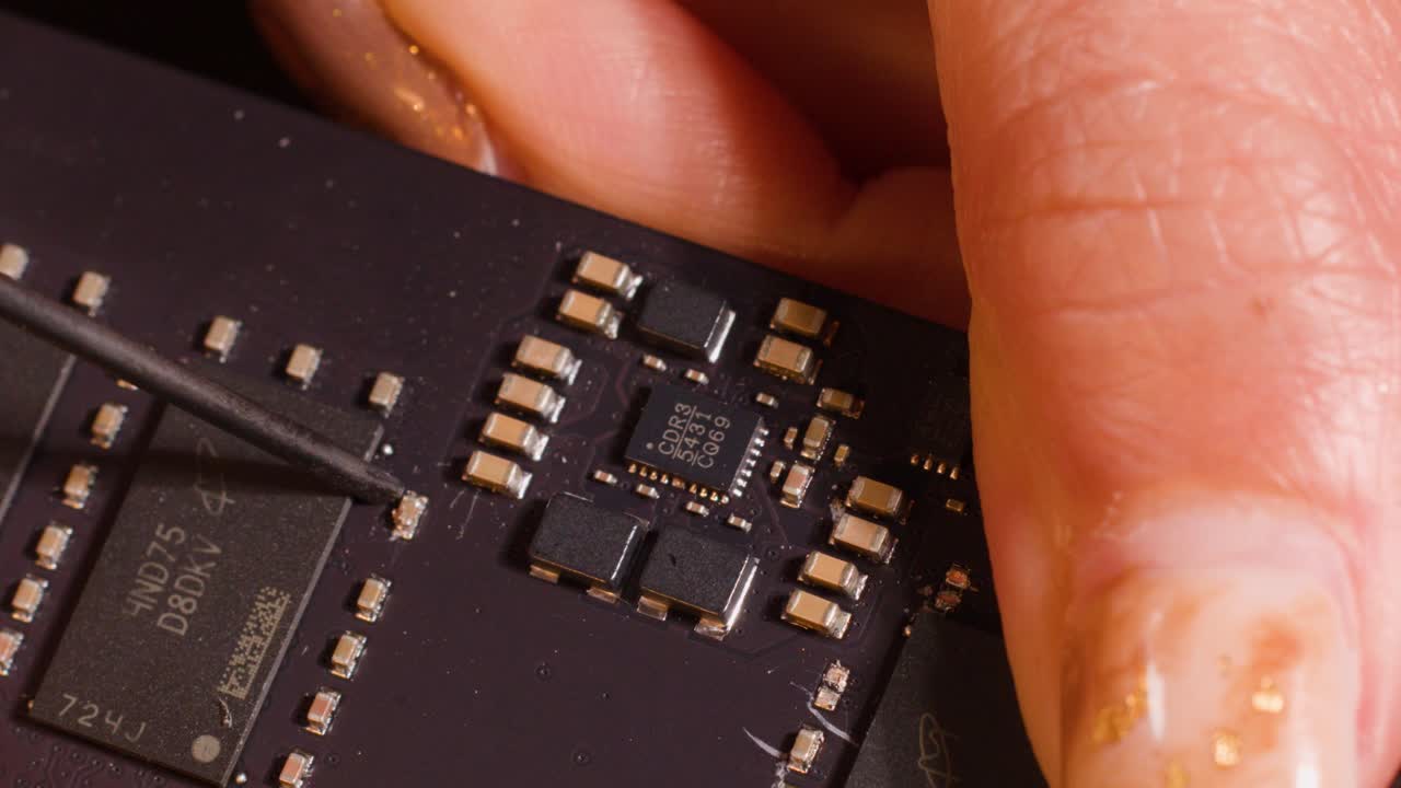 Close-up macro shot of a technician using a precision tool to repair a computer motherboard