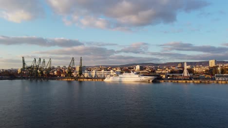 yate blanco en el puerto de varna drone disparado volando hacia el barco y el muelle con cielo nublado