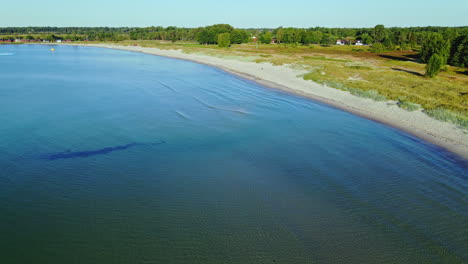 serene view along the coastline with calm blue waters and green landscapes in sandbybadet, öland, sweden - drone shot (forward)