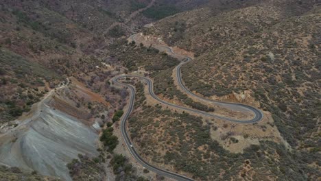 Panorámica-Aérea-Hasta-El-Coche-Que-Viaja-Por-Una-Carretera-De-Montaña-árida-Con-Curvas,-4k