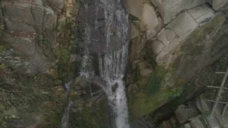 aerial footage: water flows along a small river up to a large waterfall