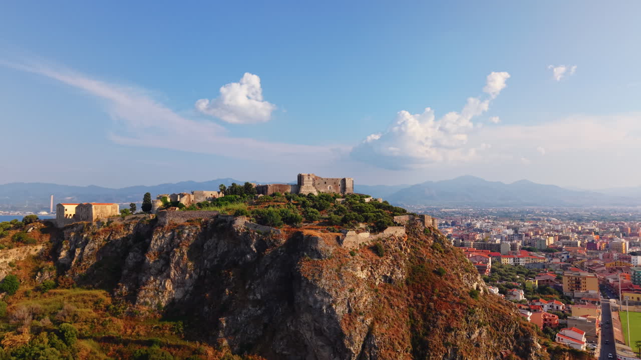 Veduta aerea di una città balneare siciliana con un castello storico su una scogliera, Italia, un punto di riferimento iconico.