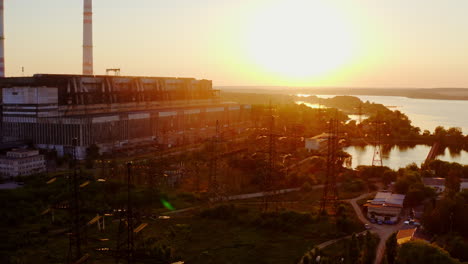 industry in nature. high-voltage electric lines and industrial plant near the river at sunset. pollution the environment.