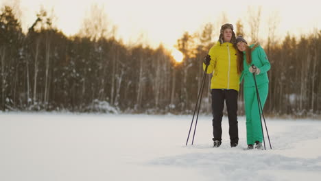 a man embraces a woman standing in the woods at sunset after a winter walk on skis. st. valentine's day. romance and warm feelings of lovers. slow motion