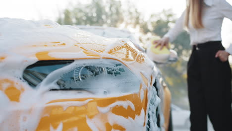 woman washing a yellow car with foam