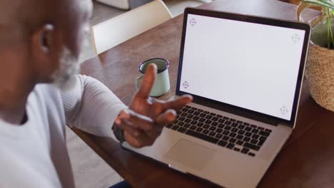 Happy-senior-african-american-man-sitting-at-table-and-using-laptop-with-copy-space,-slow-motion