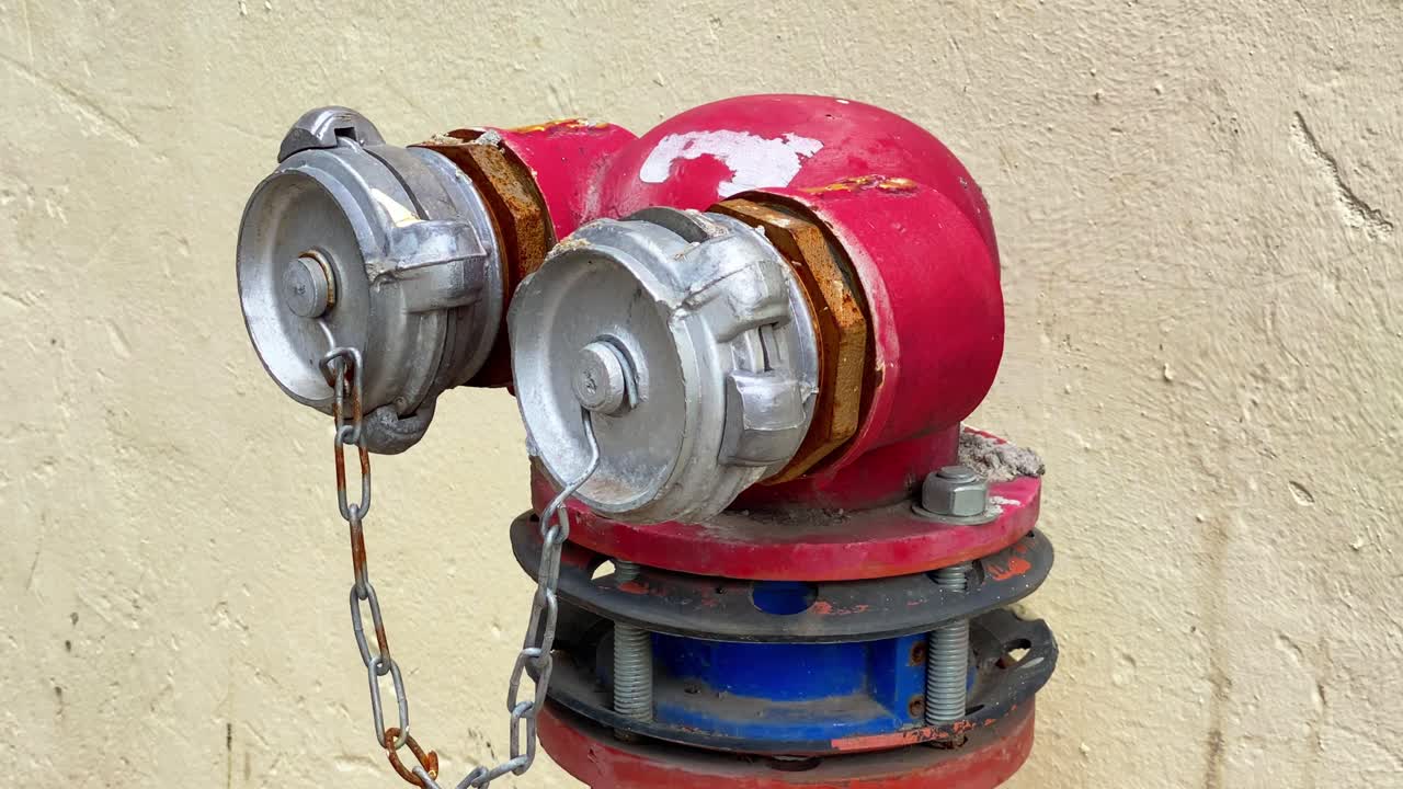 Close-up shot of a rusty red fire hydrant with metal caps and chains secured in place. Useful for emergency services, safety infrastructure, urban scenes, and firefighting themes