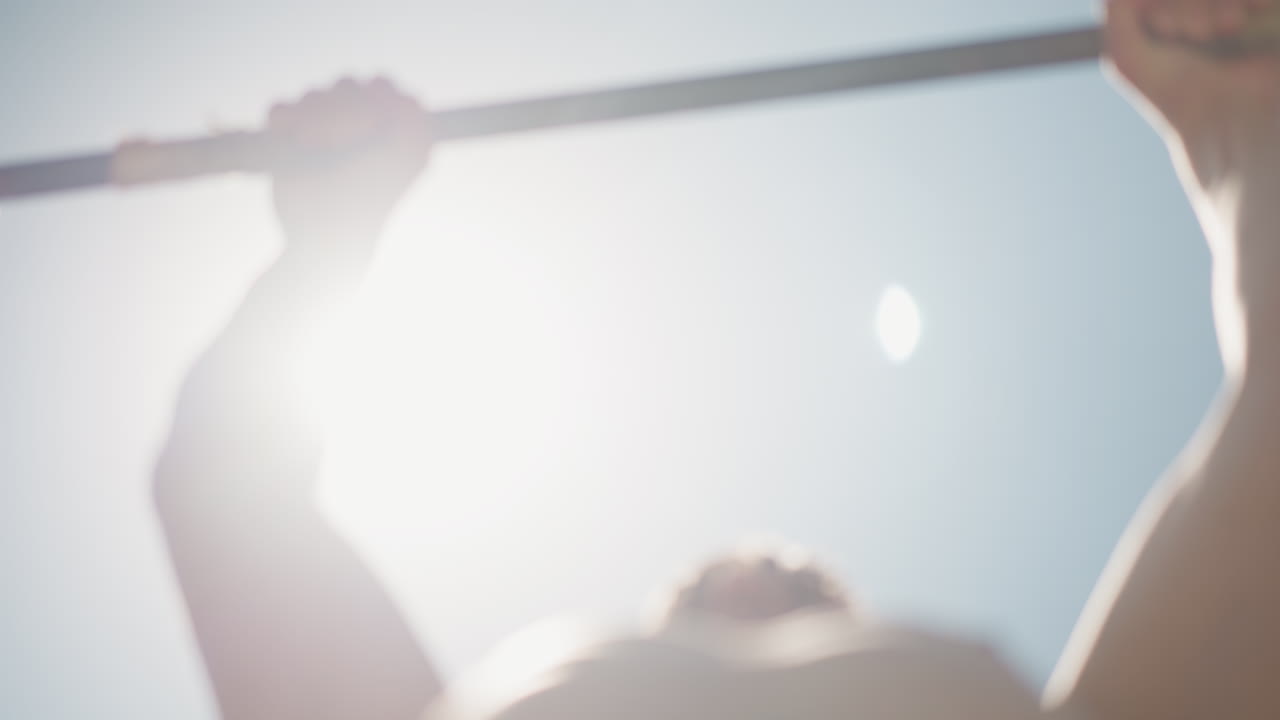 몸매가 좋은 남자가 밖에서 턱걸이를 하고, 운동을 좋아하는 사람이 밝은 햇빛 아래 야외에서 몸을 들어 올리고, 피트니스 애호가가 맑고 화창한 하늘 아래 야외 근력 운동을 해요.