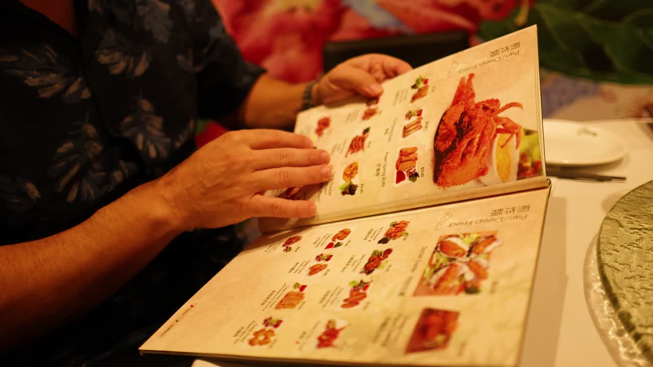A person examines a menu in a warmly lit restaurant, focusing on various dishes and options