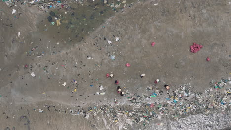 People-work-together-to-clean-up-rubbish-covered-beach,-aerial-top-down-view,-Ham-Tien-Vietnam