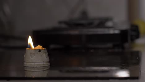 remnants of lit candle on a kitchen table with out-of-focus background