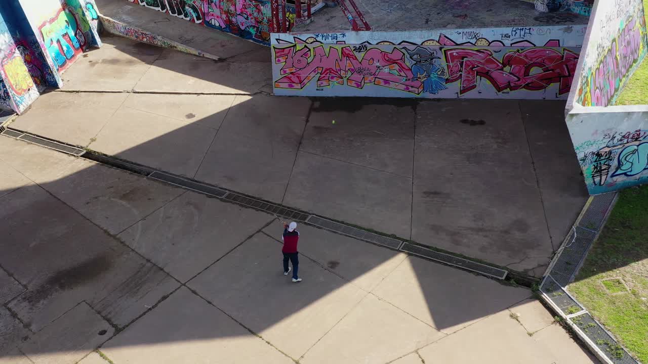 Uomo che gioca a fronton tennis su un muro graffitato, parco pubblico, anfiteatro urbano moderno