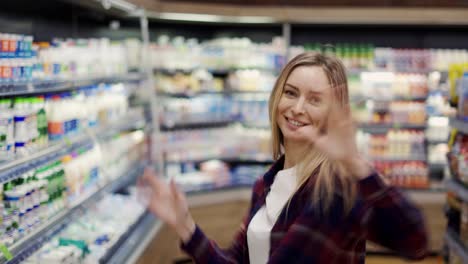 una joven feliz baila entre los pasillos de la tienda, girando, divirtiéndose