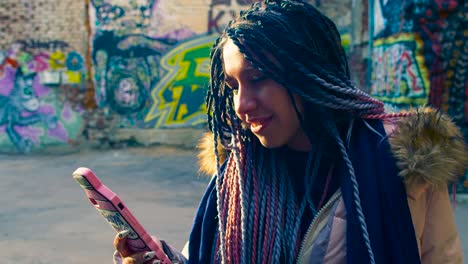 mujer joven mirando su teléfono en una ciudad con graffiti