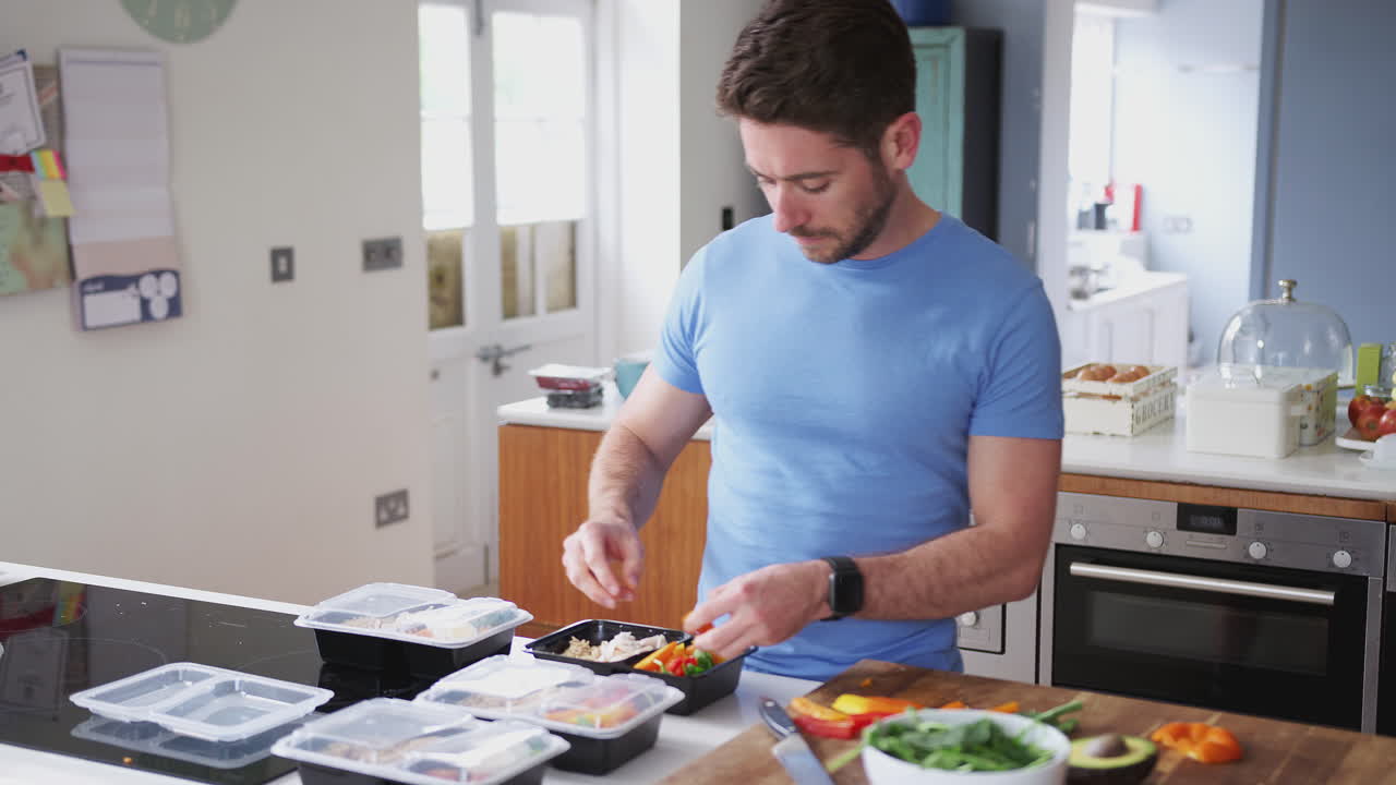 hombre vestido con ropa de fitness preparando un lote de comidas saludables en casa en la cocina