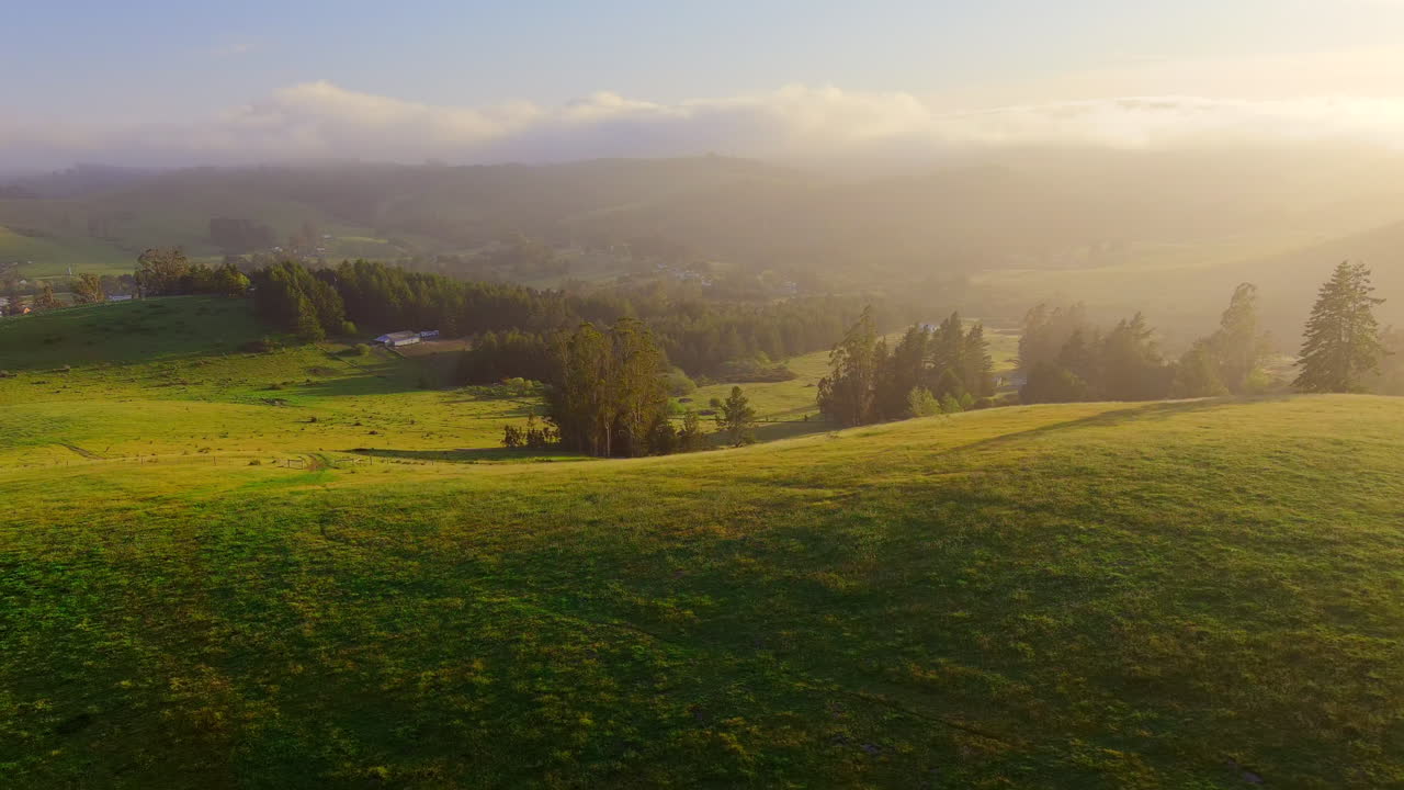 Solstråler og aftendisen over grønne bakker i landlige Californien, luftfoto i den gyldne time