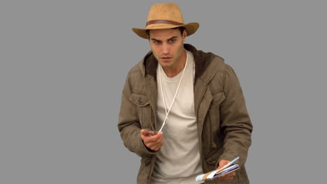 man orienteering with a map and a compass on grey screen