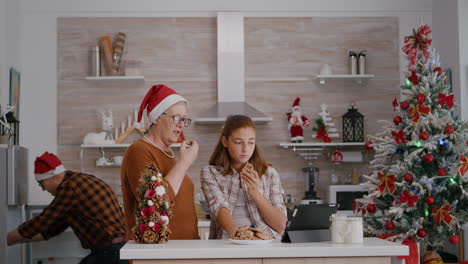 Grandmother-watching-xmas-online-video-with-granddaughter-on-tablet-while-grandfather-bringing-milk