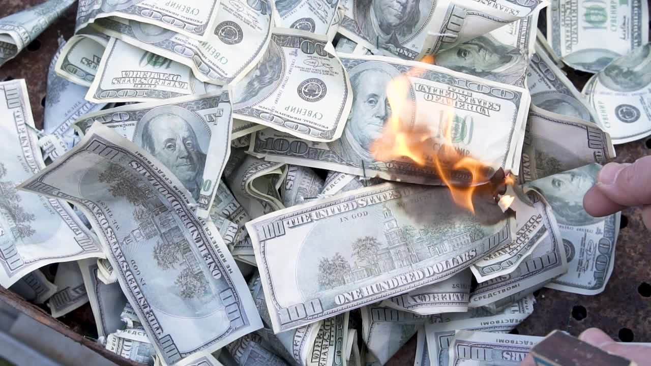 Setting fire to counterfeit dollars with a match. Burning currency. Financial crisis and depressed economy. Paper money loss concept
