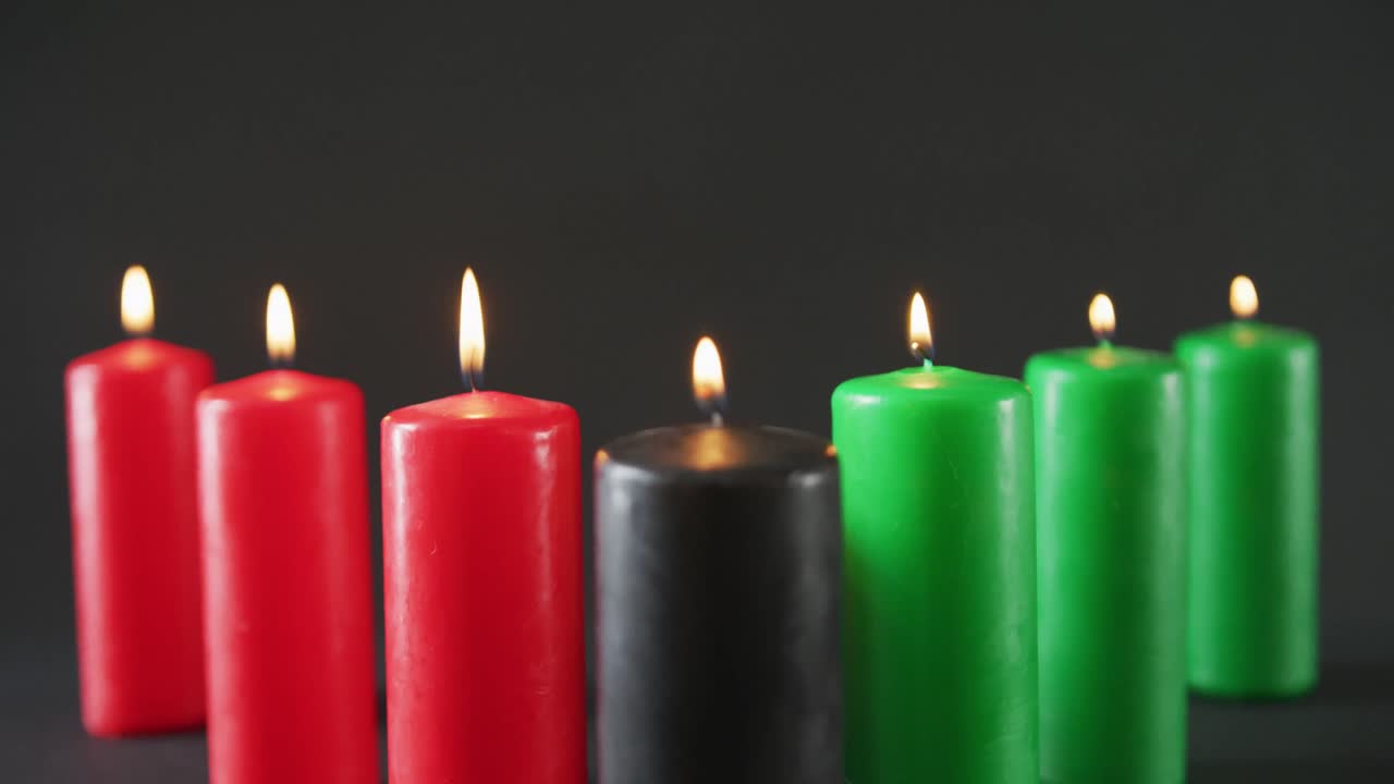 composición de velas verdes, negras y rojas encendidas de halloween contra un fondo negro