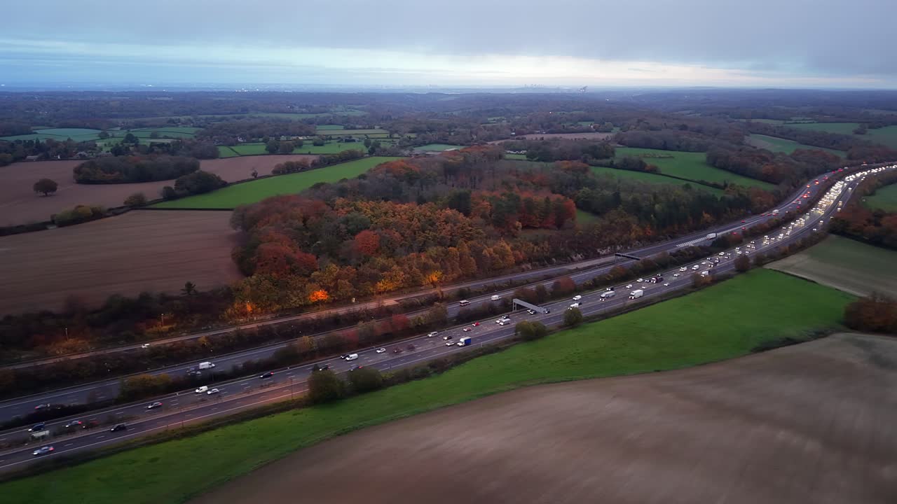 Parallax-luchtfoto van de drukke M25-snelweg die door een herfstlandschap slingert