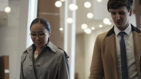 business woman and businessman talk while walking in the hotel