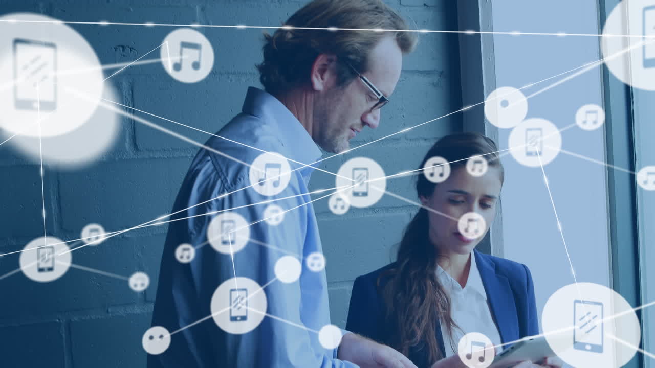 анимация сети цифровых икон над разнообразным мужчиной и женщиной, обсуждающими планшет в офисе
