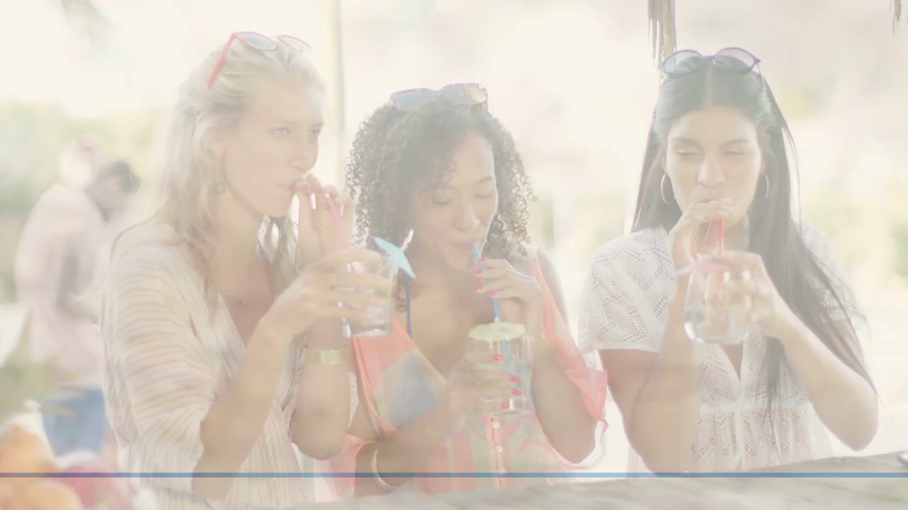 Three women sipping at outdoor bar, milkshake, right woman raising glass drawing shared toast, food