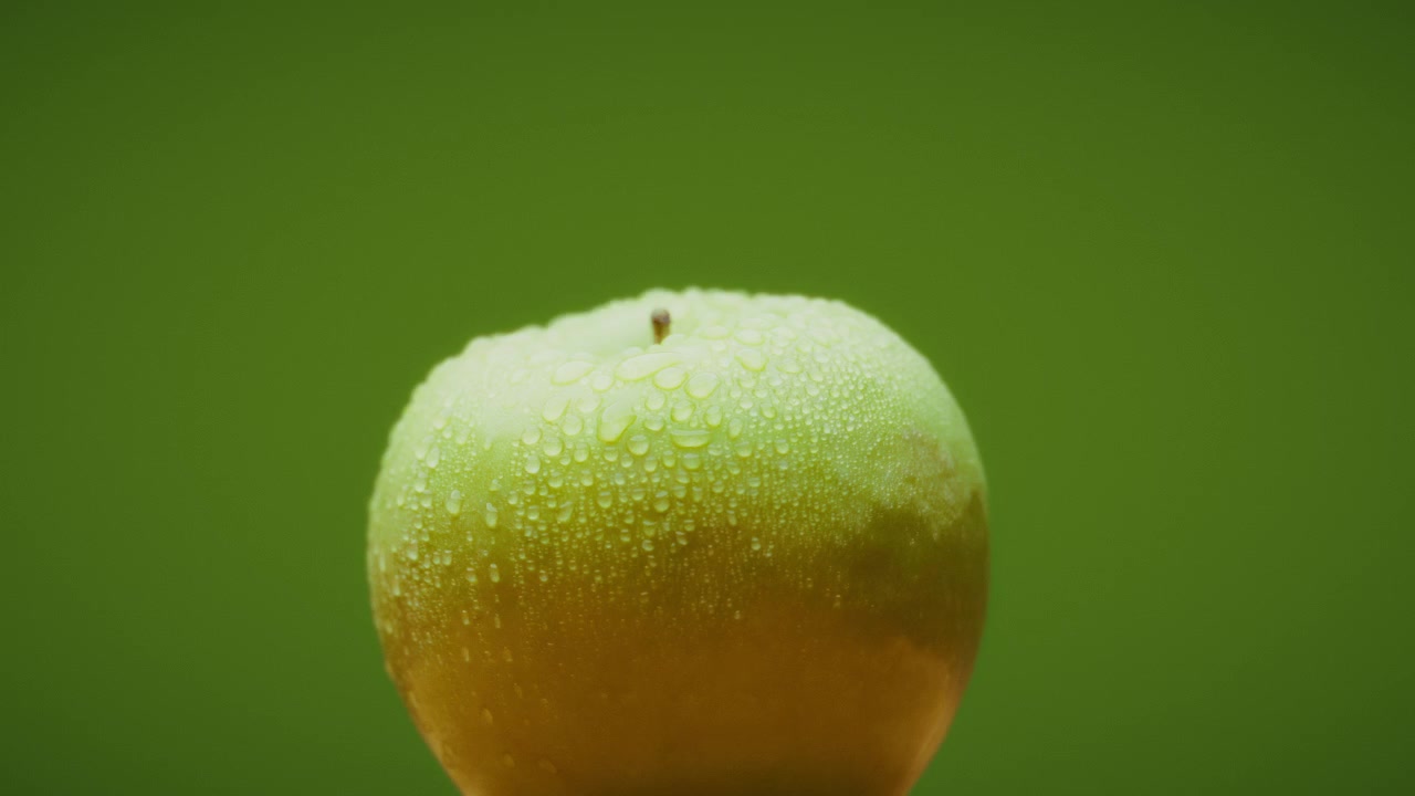 Mela verde con gocce d'acqua che appaiono e scompaiono, design creativo