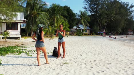 young women with travel bags just arrived on paradise tropical island with sandy exotic beach, taking selfie photos in thailand